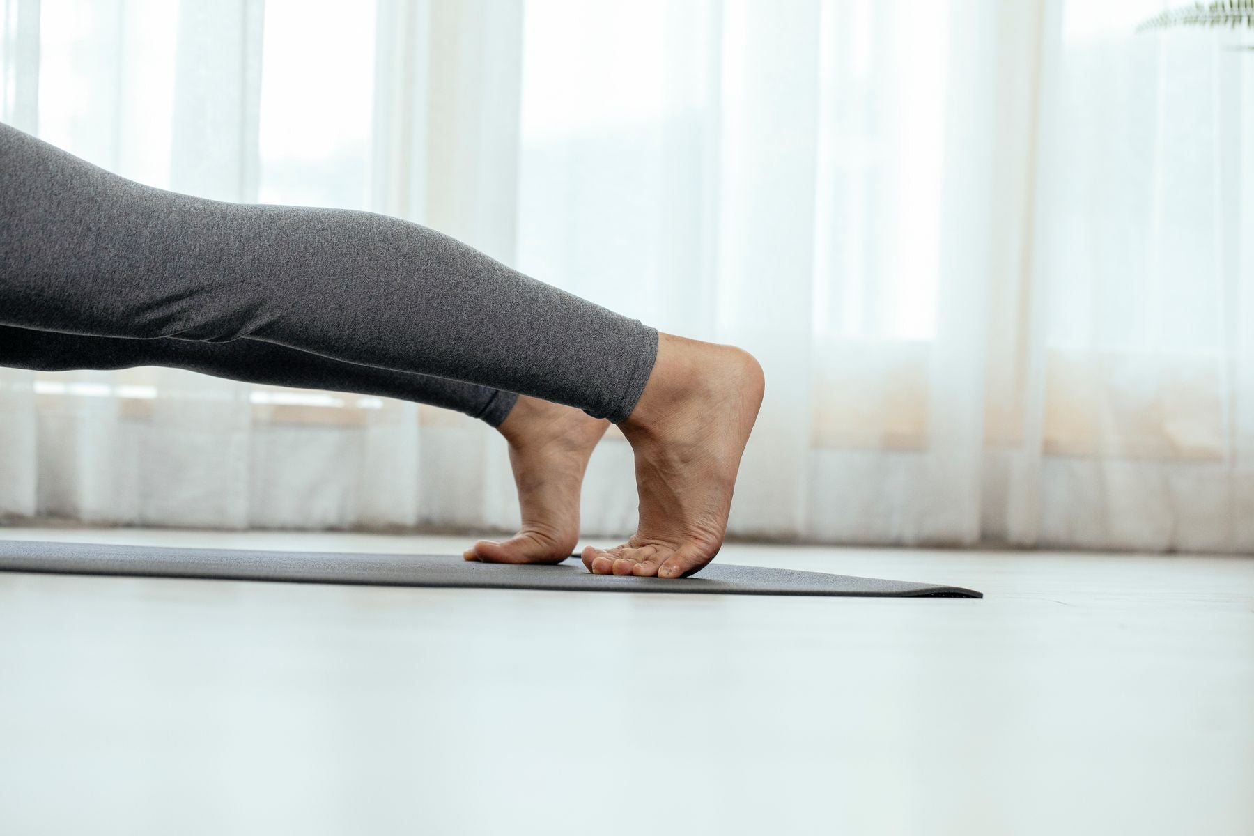 Pieds posés sur un tapis d'exercice dans une pièce baignée de lumière