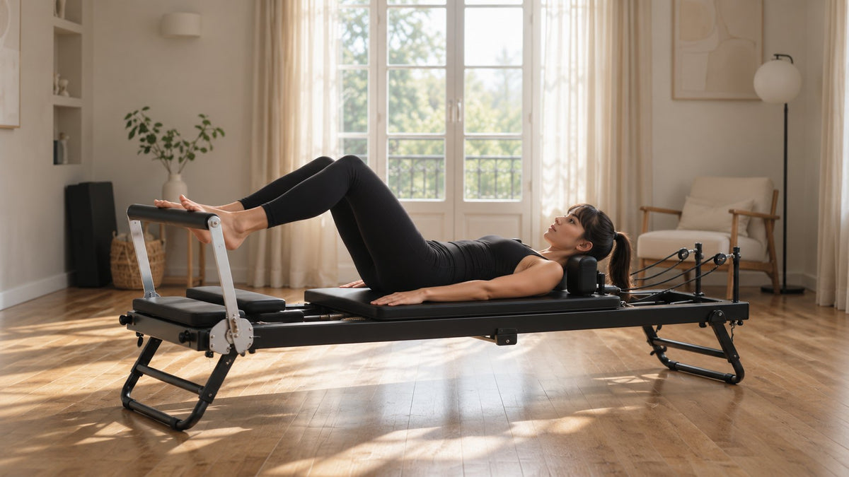 Une femme fait du Pilates sur Le Pli, machine de Pilates reformer pliable, dans un salon lumineux